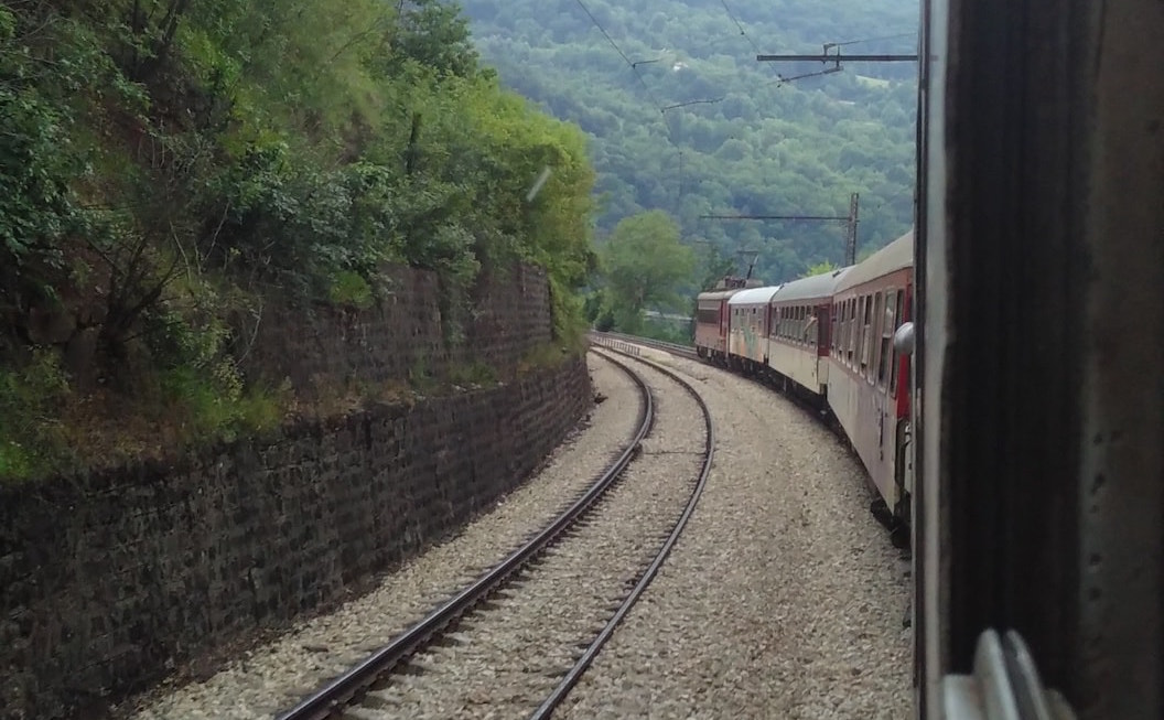 Picture shows a view of train tracks cutting through tree covered hills.