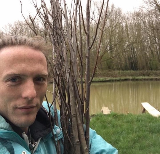 Picture shows Paul taking a selfie with some newly planted trees. He is wearing a light blue anorak, and you can see the canal and trees in the background. 